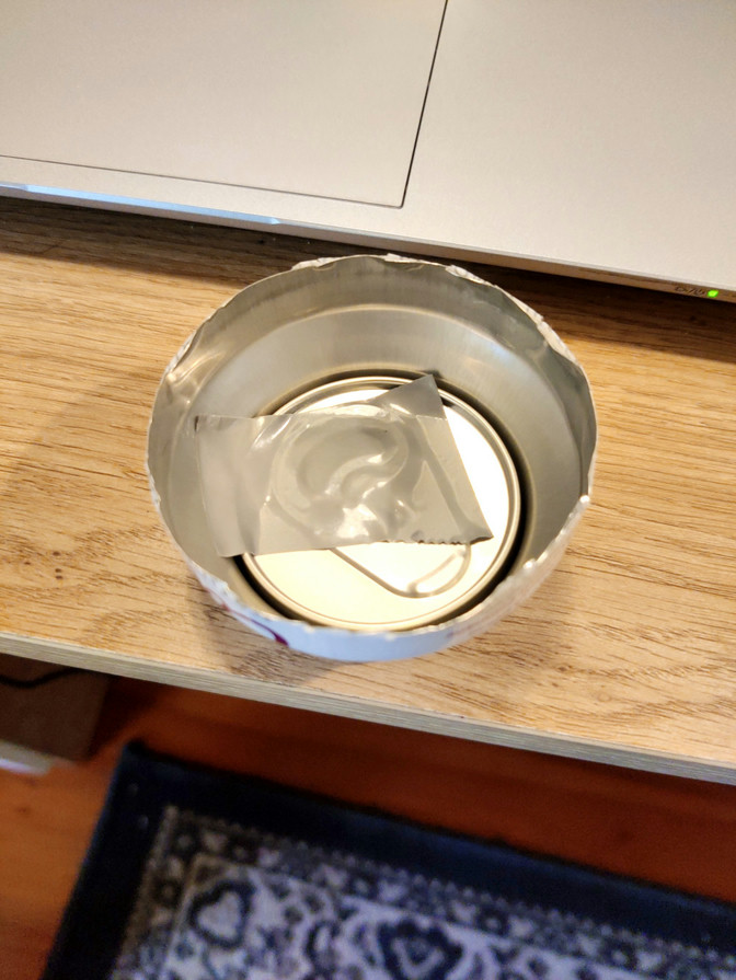 The top of a coconut water can with sticky tape sealing the inside